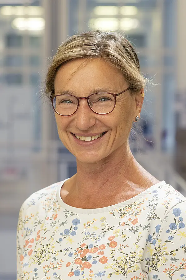 Portraitfoto von einer Mitarbeiterin mit blauer Strickjacke