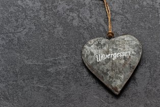 Herz aus Stein auf grauem Grund mit der Inschrift "unvergessen"